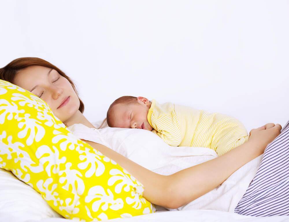 A mom and her newborn baby are sleeping