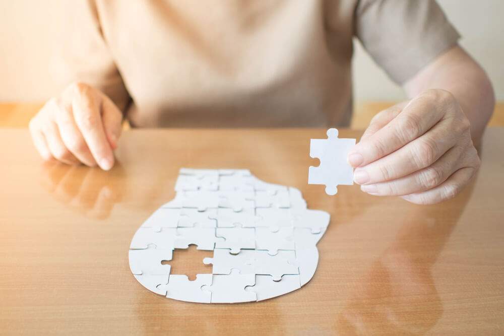 A woman is holding a piece of a brain-shaped puzzle