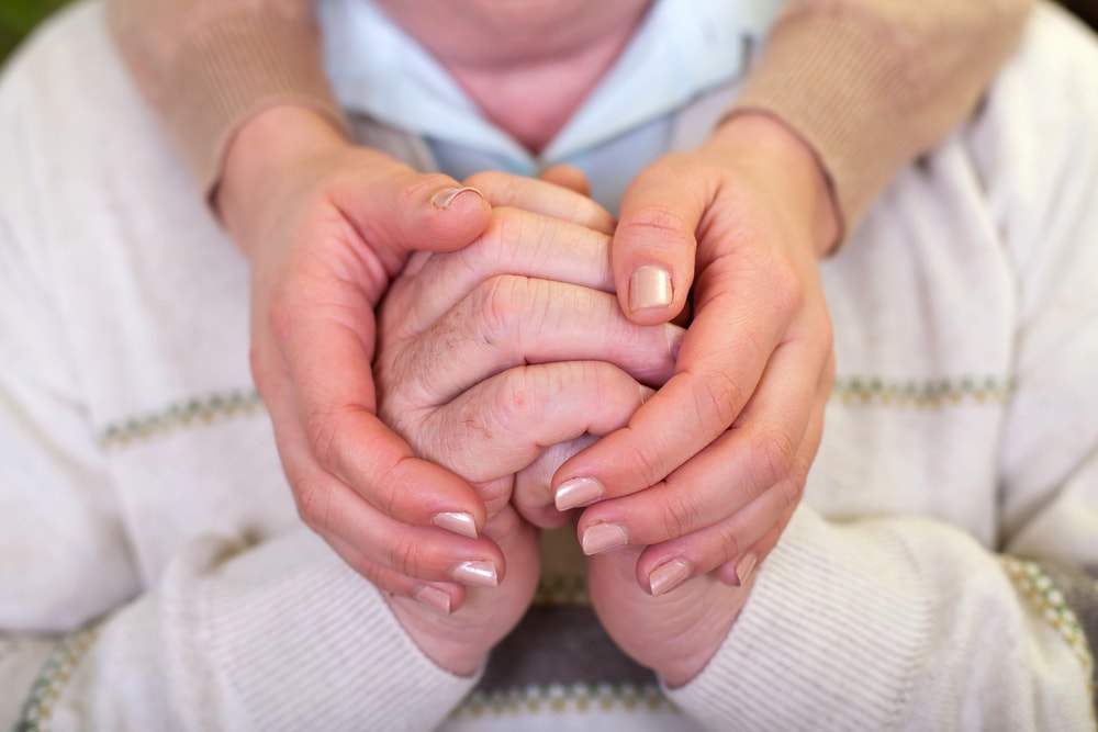  A woman is holding the hands of a dementia patient