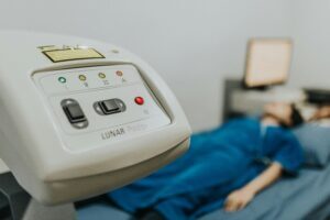 Medical examination setting with patient lying on bed, focus on healthcare device.